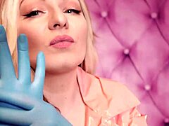 Aria Grander, zapeljiva MILF, nosi fetišistično obleko, vključno z roza PVC plaščem in modrimi rokavicami iz nitrila, ki prikazujejo njene osupljive obline v tem domačem videu