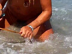 ผู้หญิงที่เป็นผู้ใหญ่ที่มีการเจาะหัวนมแบบยืดและเจาะหีหลายครั้งบนชายหาด