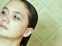 Attraktiv brunettemodel bader i varmt brusebad