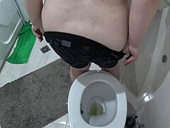 Zrelá žena s veľkými prsiami je zachytená skrytou kamerou na záchode
