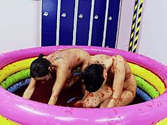 Lesbianas con grandes tetas falsas disfrutan luchando en una piscina de gelatina
