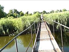 Sexig strandflicka i kostym promenerar på en hängande bro i allmänhet